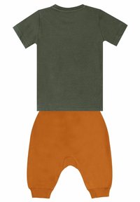 Camiseta de manga corta verde oliva combinada con pantalones jogger de cintura elástica naranja. Tejido de algodón con una textura suave y lisa.