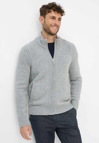 Hellgrauer Reißverschluss-Pullover mit hohem Kragen und gerippten Bündchen. Hergestellt aus Strickstoff, mit Seitentaschen und strukturierten Designelementen.