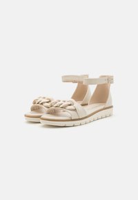 Beige Sandalen mit geflochtenem Oberteil, Knöchelriemen und einer strukturierten Sohle für besseren Halt. Hergestellt aus synthetischem Material mit einer glatten Oberfläche.