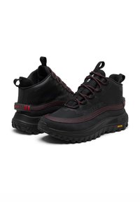 Bottes de randonnée noires avec tige synthétique texturée, accents rouges et semelle en caoutchouc à motifs. Présente un col rembourré et des lacets pour un ajustement sécurisé.
