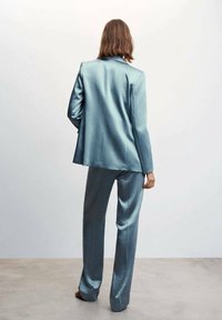 Hellblau satinierter Anzug mit maßgeschneidertem Blazer und geraden Hosenbeinen, der eine glatte Textur und ein schlankes, modernes Design präsentiert.