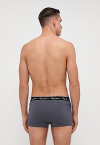 Sive pamučne bokserice s crnim pojasom na kojem je bijeli natpis "Pepe Jeans". Tkanina ima glatku teksturu.