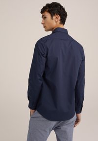 Mornarsko srajco z dolgimi rokavi s strukturiranim ovratnikom, gumbi na manžetah in gladkim, teksturiranim materialom. Ima ukrivljen rob in prilegajoč silhueto.