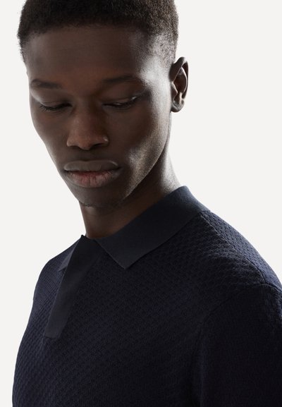 Polo shirt lavorato a maglia blu navy con un motivo testurizzato, caratterizzato da un colletto piatto a contrasto e un design slim fit.