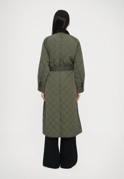 Olivegrøn quilted lang frakke med en sort krave og bælte, der har diamantmønstre og brede ærmer. Glat tekstur.