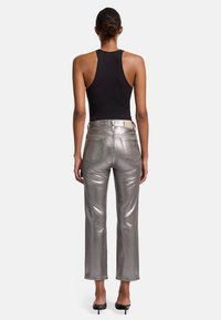 Metallisch zilveren flared broek met een hoge taille, gestructureerde naden en achterzakken, gecombineerd met een zwarte mouwloze top. Soepele textuur.