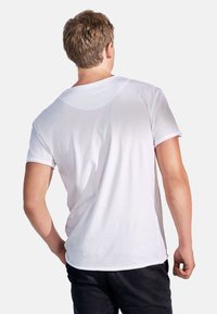 Vit bomulls t-shirt med rund halsringning och korta ärmar, som visar en mjuk textur och avslappnad passform, sedd bakifrån.