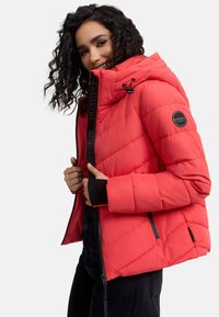Red puffer jacket with a hood, featuring diamond quilted design, black accents, zippered pockets, and branded tag on the sleeve.