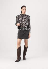 Black and white patterned long-sleeve top paired with a dark denim skirt and brown leather cowboy boots, featuring textured accents and pointed toes.