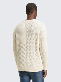 Kremast pulover z vzorcem pletenja v vrvicah, ki vključuje raznolike teksture, rebraste manšete in rob, ter sproščen kroj. Zasnovan z zadnjim panelom iz gostejše tkanine.