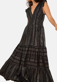 Robe maxi noire avec un décolleté en V profond, des manches à volants et des motifs métalliques complexes. Présente une jupe à étages pour plus de texture et de volume.