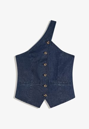 Veste asymétrique en jean bleu foncé avec une bretelle unique, six boutons sur le devant et deux poches fendues horizontales.