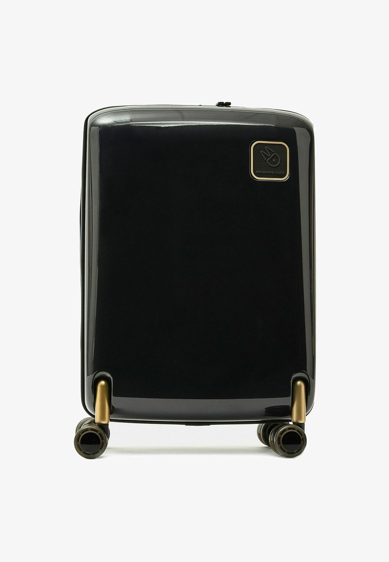 Maleta dura negra con acabado brillante, con acentos de latón, cuatro ruedas y un logo en la parte frontal. Diseño compacto, textura suave.