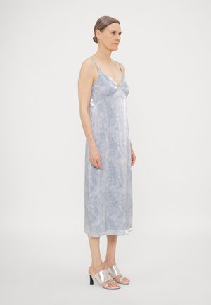 Satin blue mid-length dress with delicate spaghetti straps, textured pattern, and a slight V-neck. Paired with silver heeled sandals.