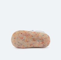 Suela de una zapatilla con una superficie texturizada en color crema y motas multicolores. El diseño incluye estrías para mejorar la tracción.
