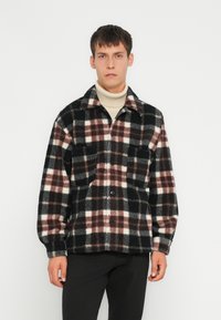 Plaid fleece särk-villane jakk mustas, valges ja burgundi värvitoonis. Omab kahte rinna taskut ja nupuga esist. Pehme tekstuur ja lõdvestunud sobivus.