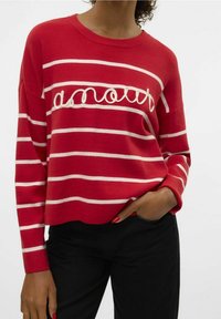 Pull rayé rouge avec larges rayures blanches horizontales et le mot "amour" en broderie blanche. Texture douce, encolure ronde, coupe décontractée.