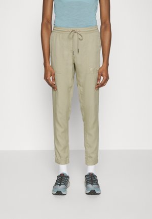 Pantalones cargo color beige claro con cintura ajustable, bolsillos laterales y puños elásticos, combinados con zapatillas deportivas azules y calcetines blancos.