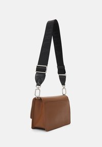 Brązowa skórzana torebka o ustrukturyzowanym prostokątnym kształcie, z czarnym regulowanym paskiem i srebrnymi metalowymi elementami.