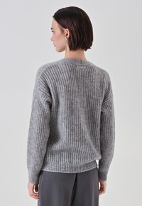 Maglione grigio lavorato a maglia con vestibilità ampia, caratterizzato da una texture a costine, scollatura rotonda e un piccolo dettaglio sul retro.