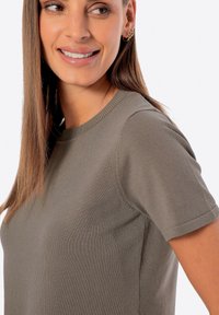 Oliwkowy t-shirt z krótkim rękawem, okrągłym dekoltem i prążkowaną teksturą, z delikatnymi detalami szwów wzdłuż ramion.