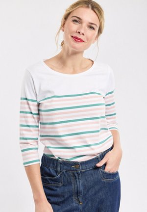 Haut à manches longues rayé en blanc, rose et teal, avec un col rond. Associé à une jupe en denim bleu foncé taille haute.