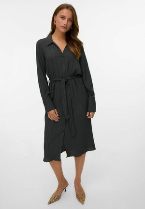 Robe longue gris foncé à manches longues avec un devant boutonné et une ceinture. Présente un tissu texturé, un col et une longueur au genou. Accentuée par des chaussures à talons hauts au motif serpent.