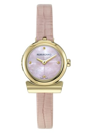 Reloj redondo de oro con esfera rosa de nácar, marcadores dorados, correa de cuero beige texturizada y logotipo de Ferragamo a las 12 en punto.