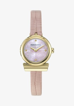Reloj redondo de oro con esfera rosa de nácar, marcadores dorados, correa de cuero beige texturizada y logotipo de Ferragamo a las 12 en punto.