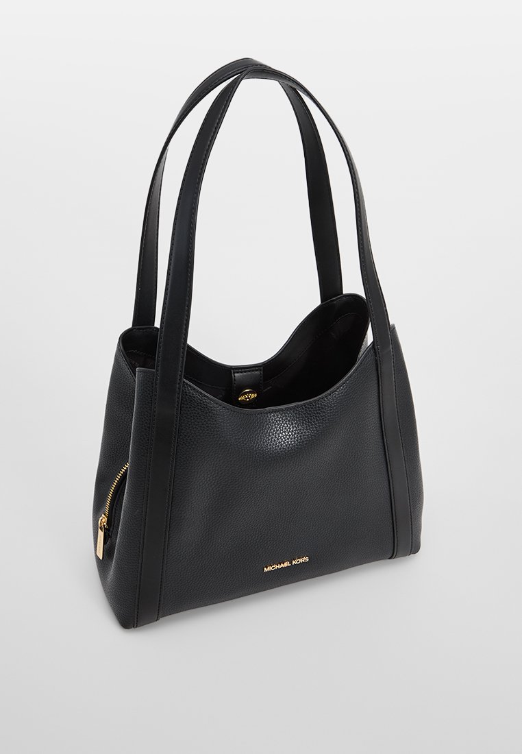 Zwarte leren tote bag met een gestructureerde afwerking, voorzien van twee lange handvatten en een gouden ritsdetail. Het logo is op de voorkant geplakt.