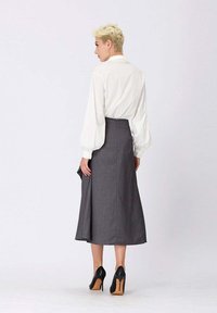 Jupe gris à rayures avec un design évasé et une longueur au genou, associée à un blouse blanche et des escarpins noirs.