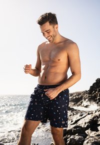 Marine zwemshorts met een speels patroon van kleurrijke iconen. Elastische tailleband met aantrekkoord, gemaakt van een lichte, ademende stof.