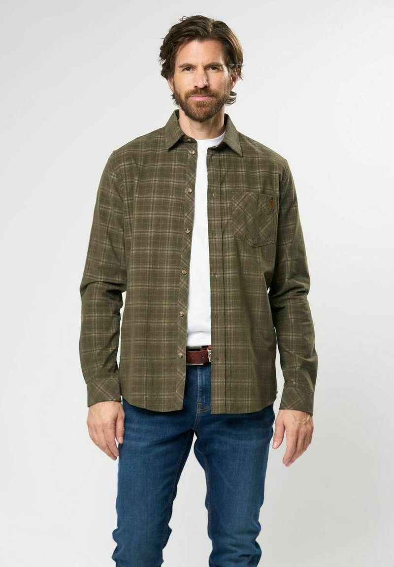 Grön rutigt flanellskjorta med knapp-up framtill, bröstficka och långa ärmar. Bärs över en vit skjorta, ihop med blå jeans.