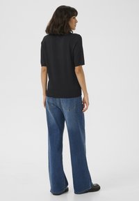 Zwarte, kortoevers top met een geribbelde zoom, gecombineerd met losse, blauwe denim jeans met een rechte snit en een klassiek achterzakontwerp.