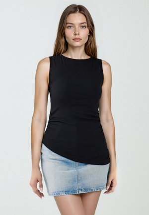 Top nero senza maniche con texture a coste e orlo arrotondato, abbinato a una minigonna di jeans azzurri con design aderente.
