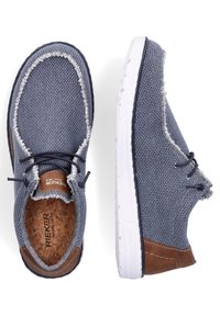 Chaussures en tissu texturé bleu avec des accents en cuir brun, semelles blanches et couture contrastante. Comprennent des lacets et une semelle intérieure à texture liège.