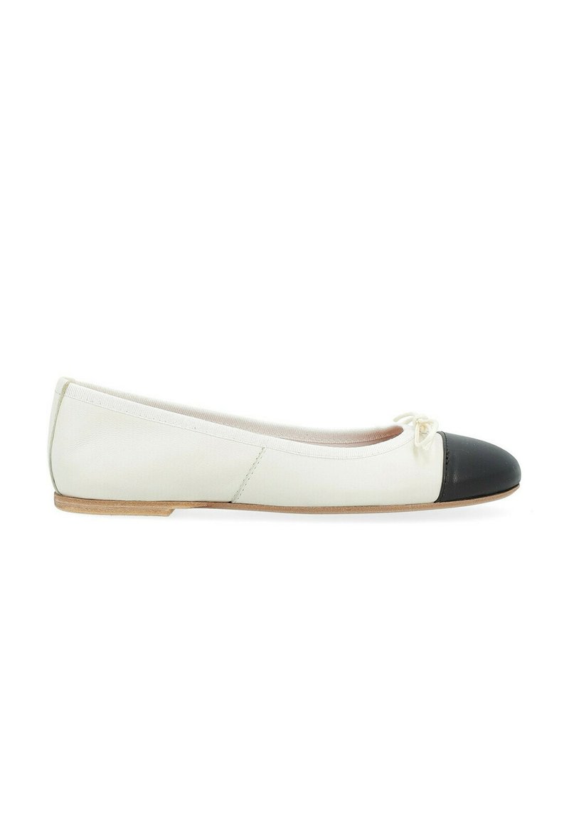 Ballerines en cuir blanc avec un embout en vernis noir, semelle plate et un petit nœud à l'avant. Texture lisse sur toute la surface.
