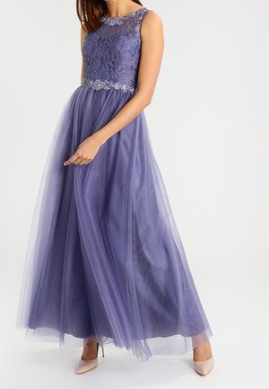 Lawendowa sukienka bez rękawów z koronkowym gorsetem, pasem zdobionym koralikami i zwiewną tiulową spódnicą, noszona z beżowymi szpilkami.