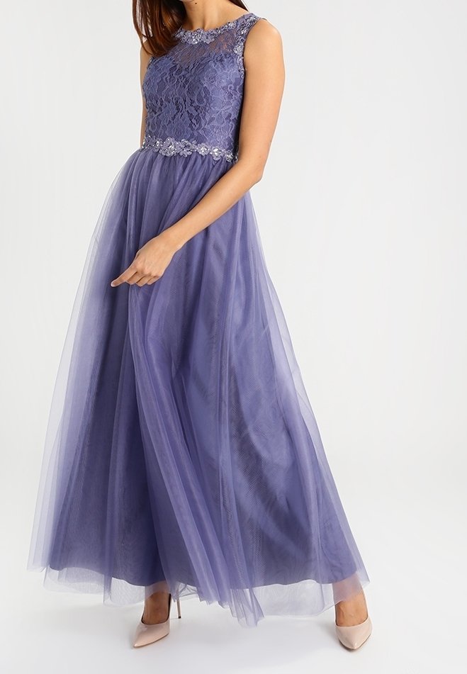 Robe lavande sans manches avec corsage en dentelle, taille perlée et jupe fluide en tulle, portée avec des talons hauts beige.