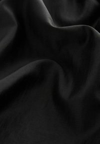 Sort stof med en glat tekstur, der præsenterer bløde draperinger, som indikerer en let sammensætning. Ingen synlige mønstre eller hardware.
