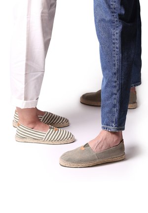 Striped green and white canvas espadrilles with a brown accent and jute soles, paired with grey canvas espadrilles, viewed from mid-calf down.