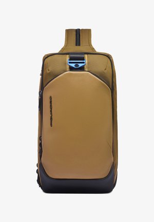 Brauner und schwarzer Rucksack mit einem einzelnen Trageriemen, vorderer Schutzplatte, seitlichen Reißverschlusstaschen und einer blauen Schnalle am oberen Riemen.