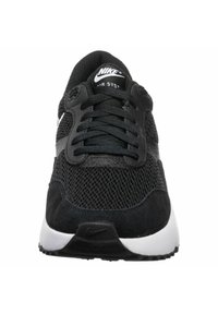 Scarpa sportiva nera con tomaia in mesh e dettagli in suede, punta tonda, lacci e suola bianca con il marchio sulla linguetta e sul tallone.