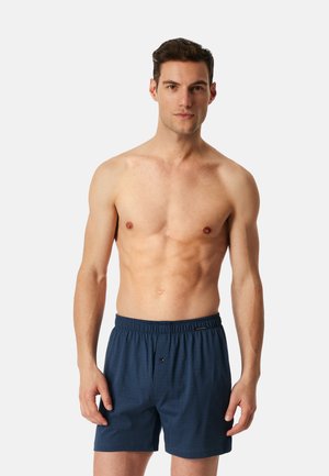 Blaue gewebte Boxershorts mit elastischem Bund, die einen Knopfverschluss vorne und ein dezentes geometrisches Muster aufweisen.