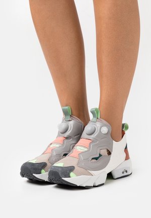 Szare buty sportowe z siateczkową cholewką, kolorowe akcenty w odcieniach brzoskwini, zieleni i brązu, z charakterystycznym zapięciem na pompkę i teksturowaną podeszwą.