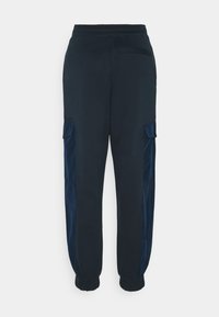 Marina joggerbyxor i mjukt tyg, med elastisk midja och sidofickor i cargo-stil som har en kontrasterande satinfåra. Viskande anklar.