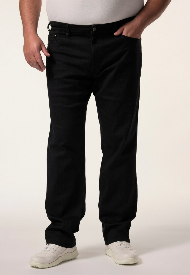 Jeans de mezclilla negra con un diseño de pierna recta, cinco bolsillos y cierre de botón, combinados con zapatillas blancas sobre un fondo neutro.