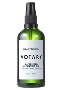 Bottiglia di vetro verde con un applicatore spray nero. Etichetta bianca con testo nero: "Votary Super Seed Cleansing Oil," con motivi. Dimensione di 100 mL.