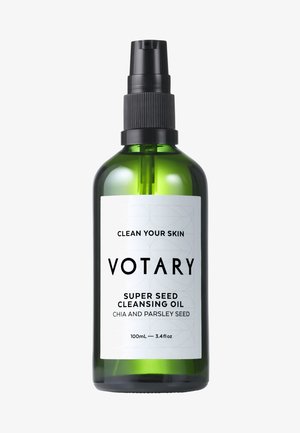 Grüne Glasflasche mit einem schwarzen Sprühkopf. Das weiße Etikett trägt schwarzen Text: "Votary Super Seed Cleansing Oil" mit Mustern. 100 mL Größe.
