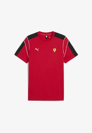 Rdeča športna majica s kratkimi rokavi, ki na levem prsnem delu nosi logo Puma in emblem Ferrarija, z črnimi detajli na rami in belim pasom.